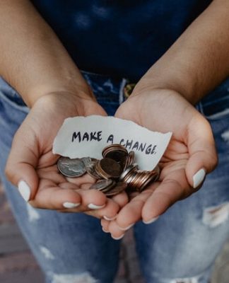 A person holds change and a strip of paper reading "Make a change"