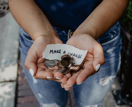 A person holds change and a strip of paper reading "Make a change"